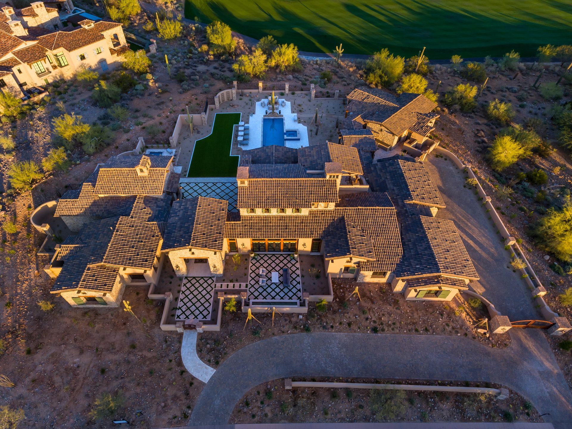 An aerial view of a large house with a pool in the middle of the desert.