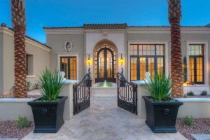 The front of a large house with palm trees in front of it.