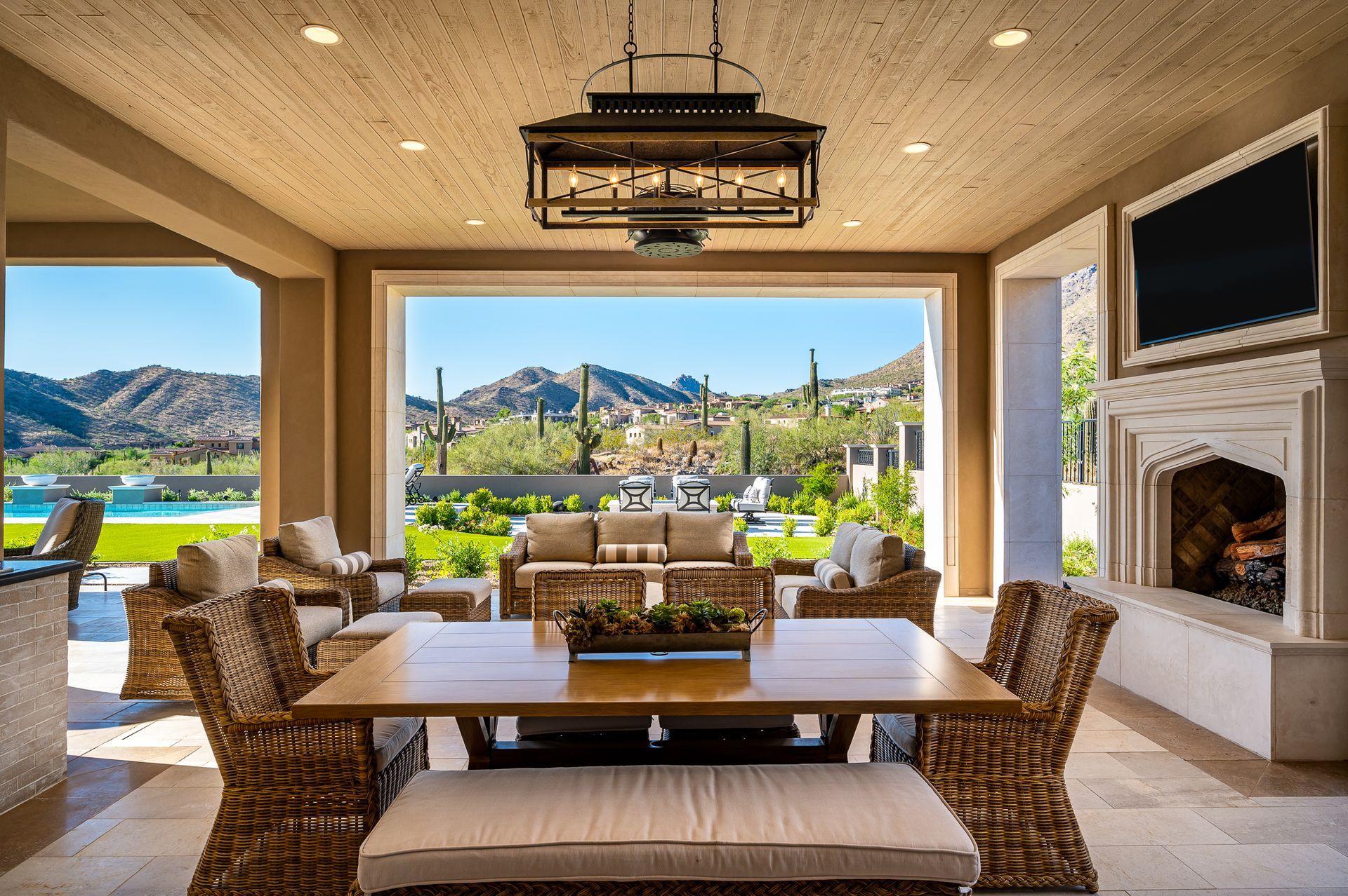 covered patio with dining table overlooking a pool and mountains