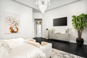 A living room with a couch , chair , television and a potted plant.