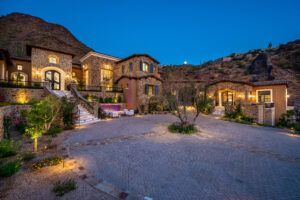 A large house is sitting on top of a hill next to a mountain.