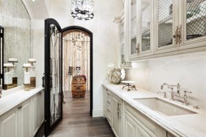 A kitchen with a sink , cabinets and a door leading to a wine cellar.