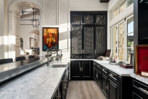 A kitchen with black cabinets , white counter tops , and a large island.