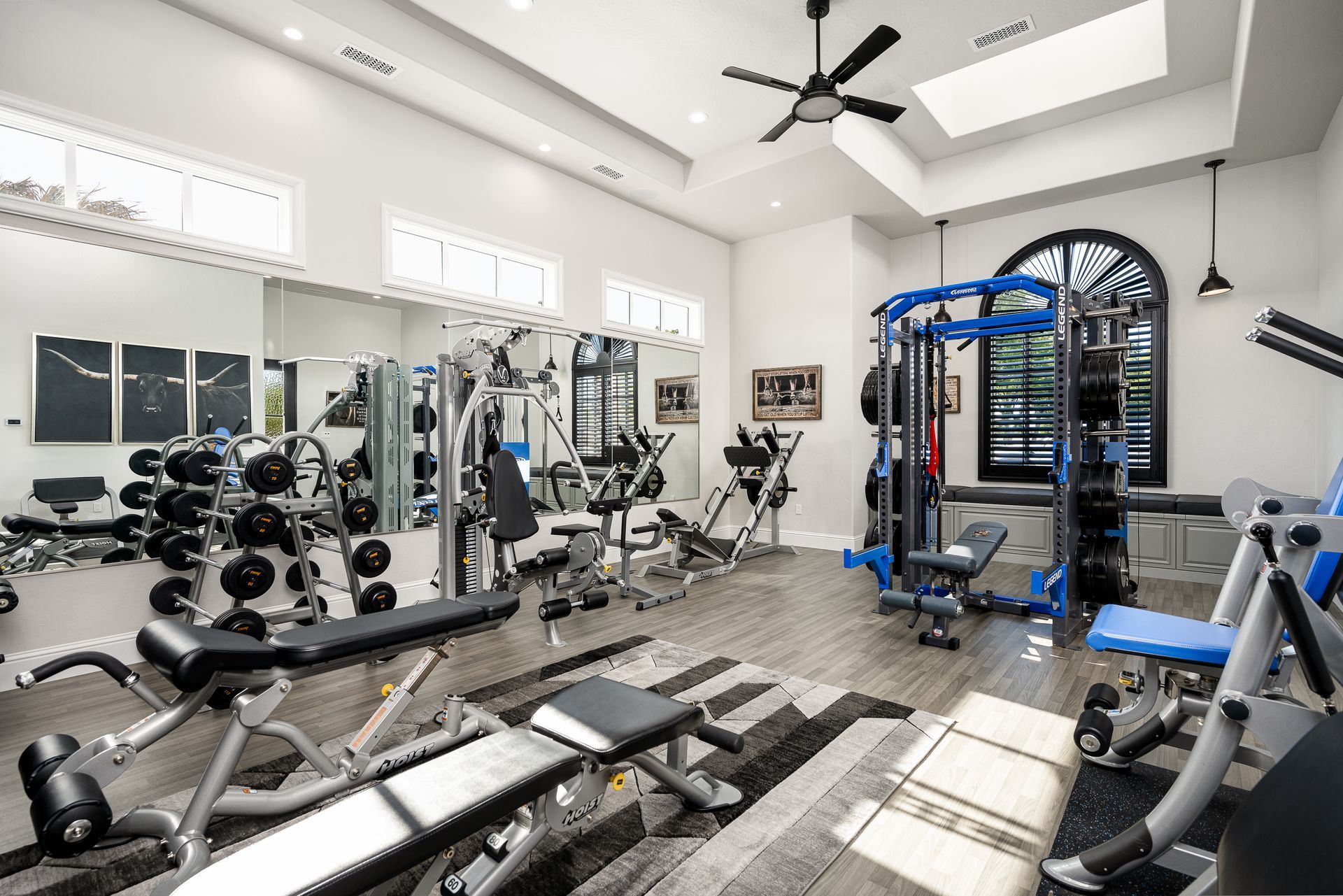 A large gym filled with lots of exercise equipment and a ceiling fan.