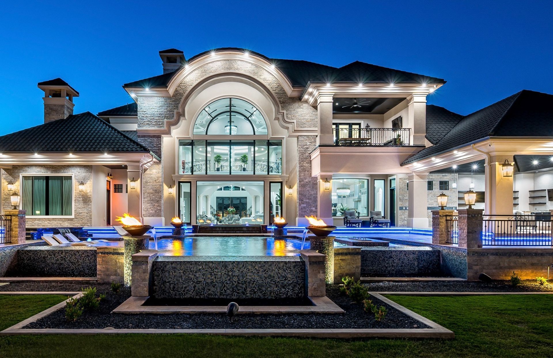 A large house with a swimming pool in the backyard at night.