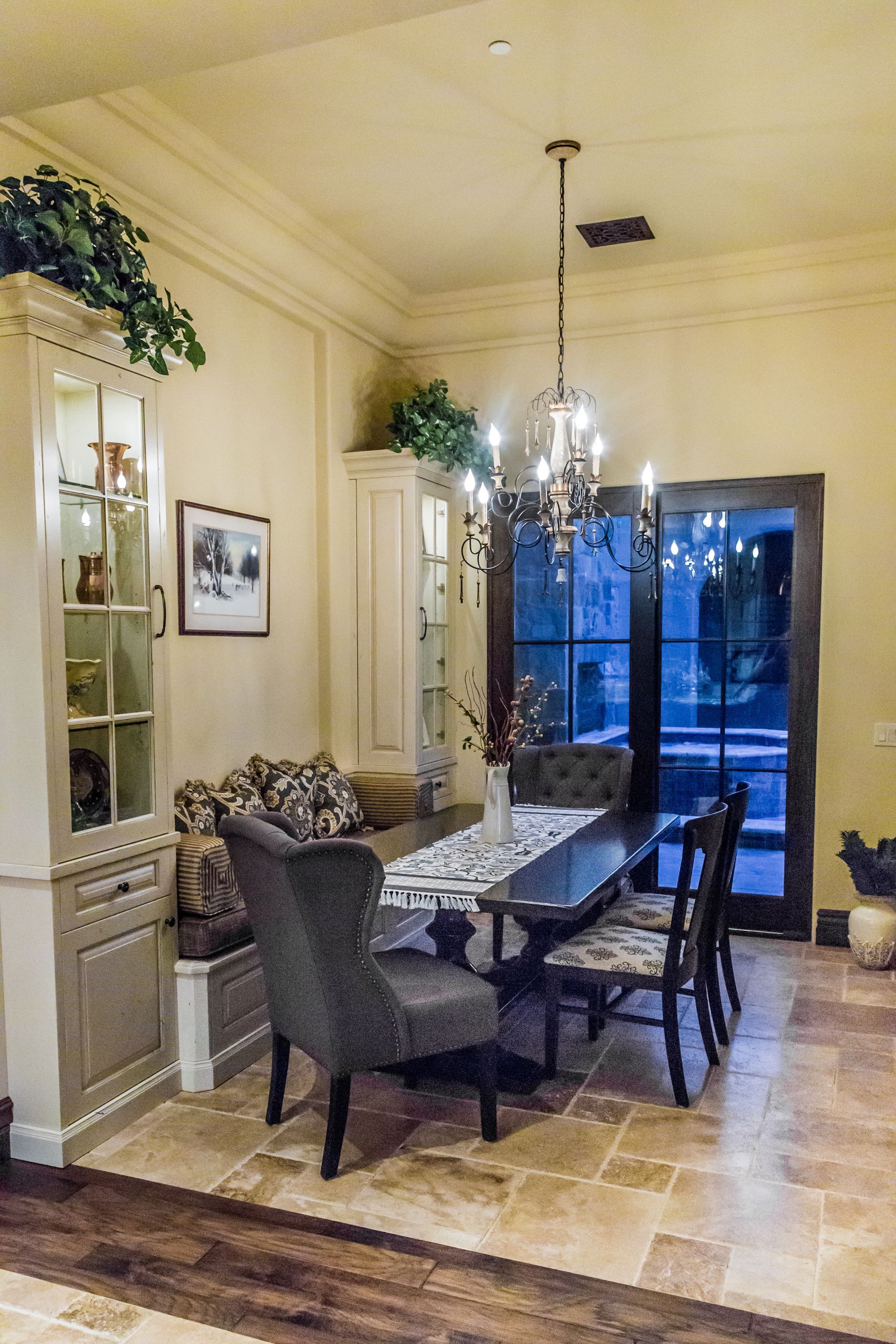 A dining room with a table and chairs and a chandelier hanging from the ceiling.