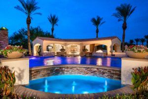 A large swimming pool with a fountain in the middle and palm trees in the background.