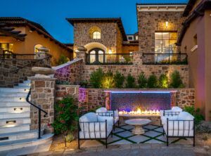 There is a fireplace in the backyard of a large house.