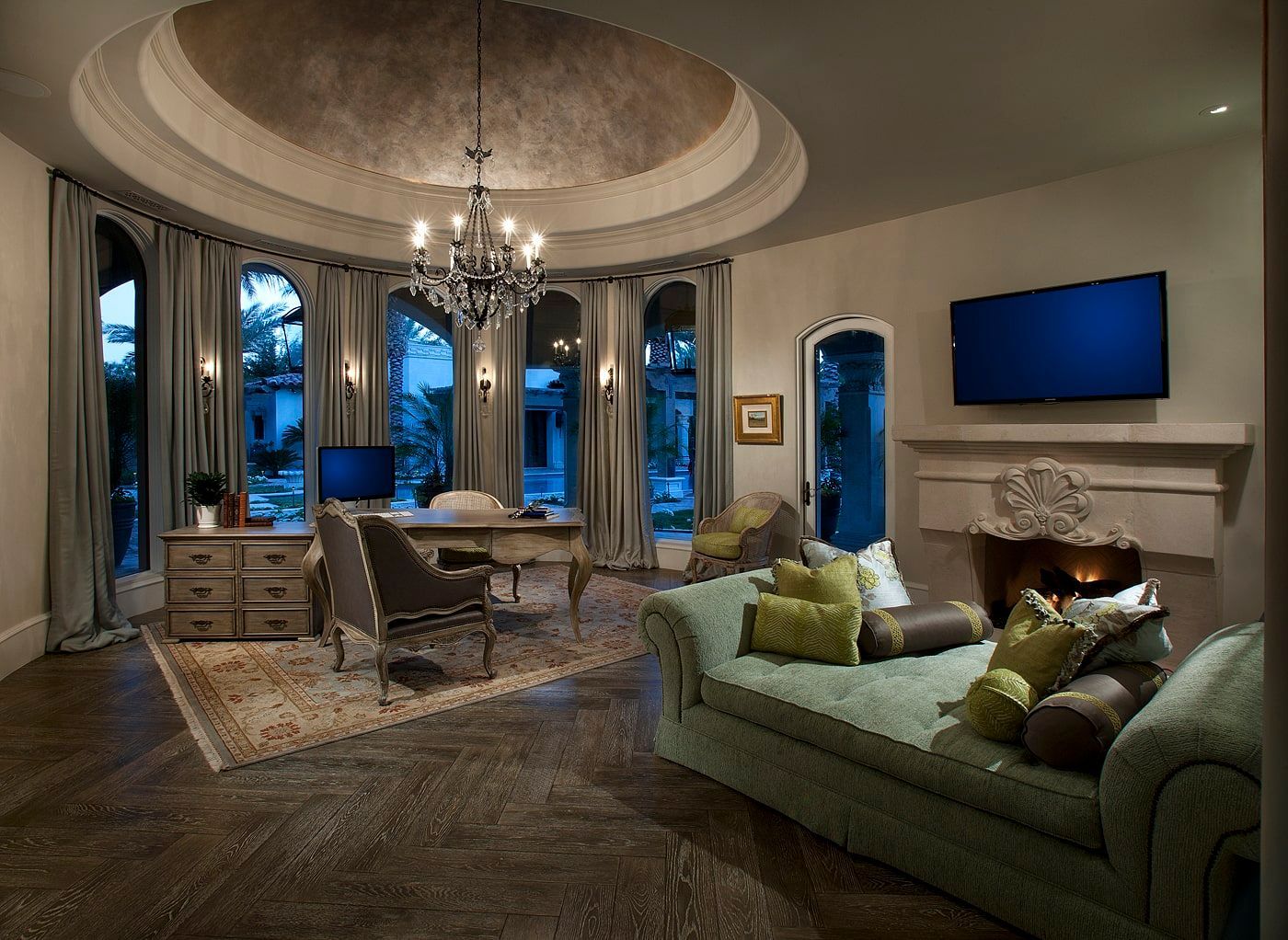 A living room with a couch , desk , television and fireplace.