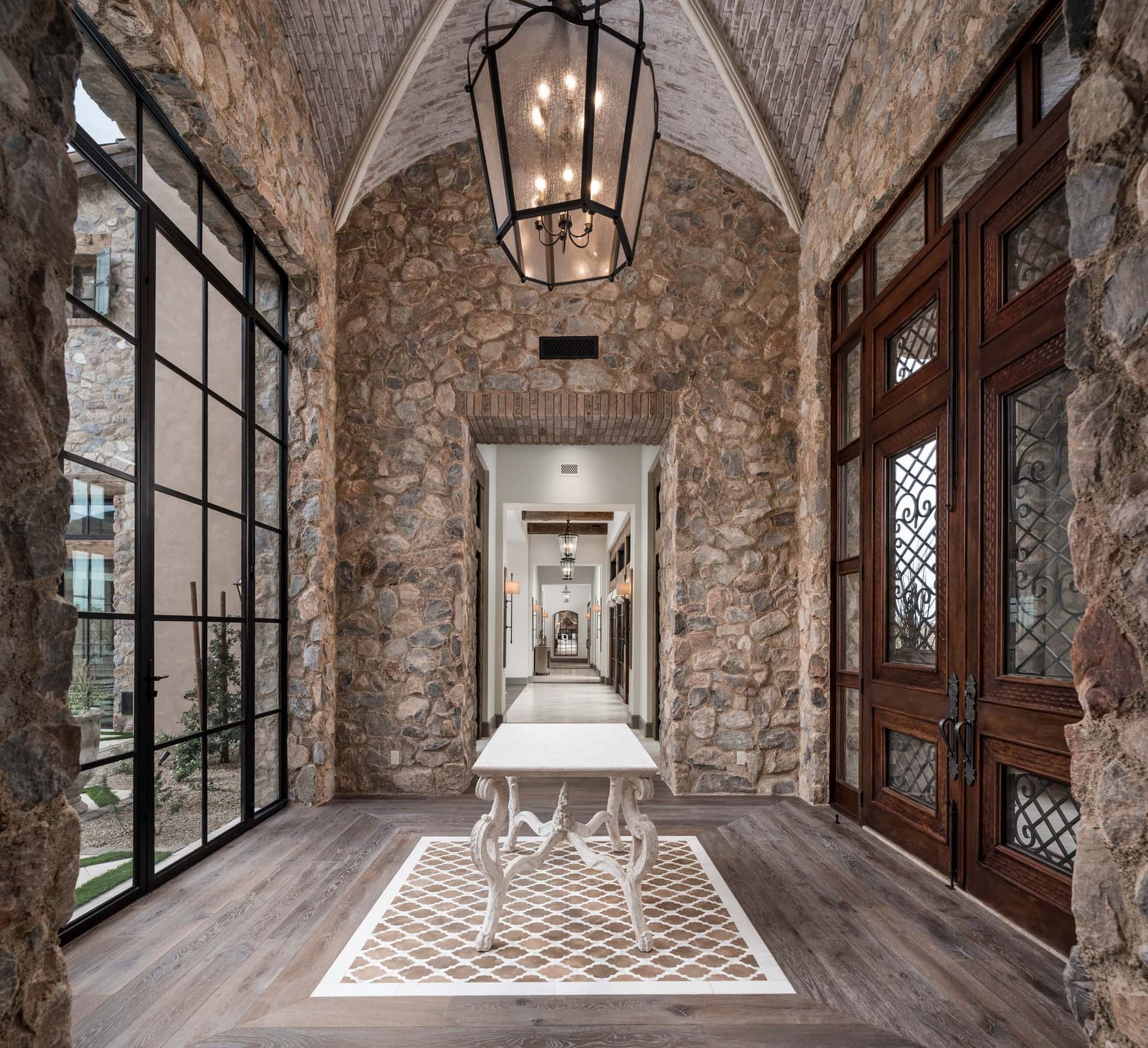 A long hallway with a table in the middle and a lantern hanging from the ceiling.