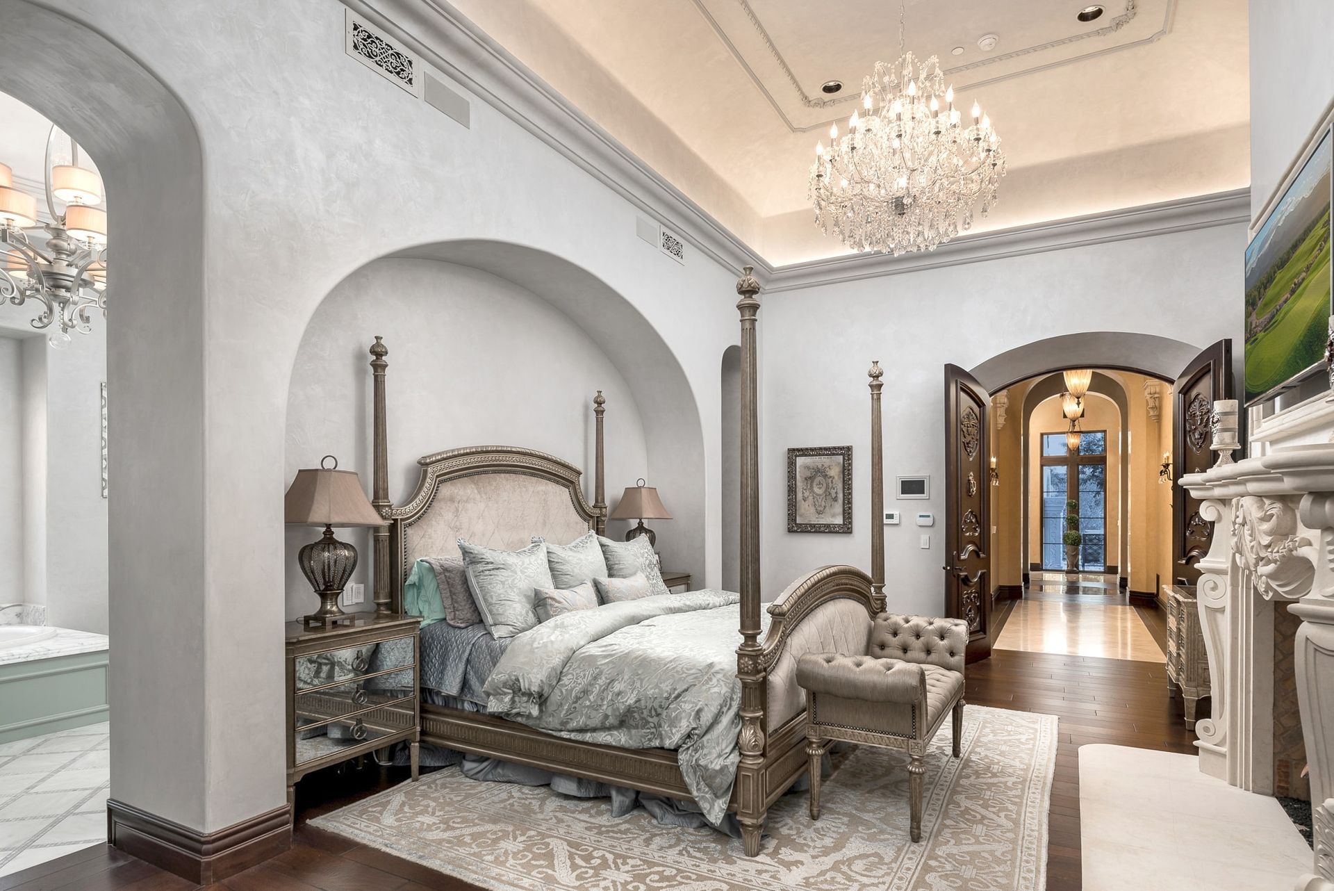 A bedroom with a four poster bed , a fireplace , and a chandelier.