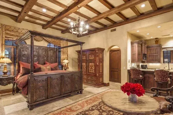 A bedroom with a canopy bed , a table , chairs , and a chandelier.