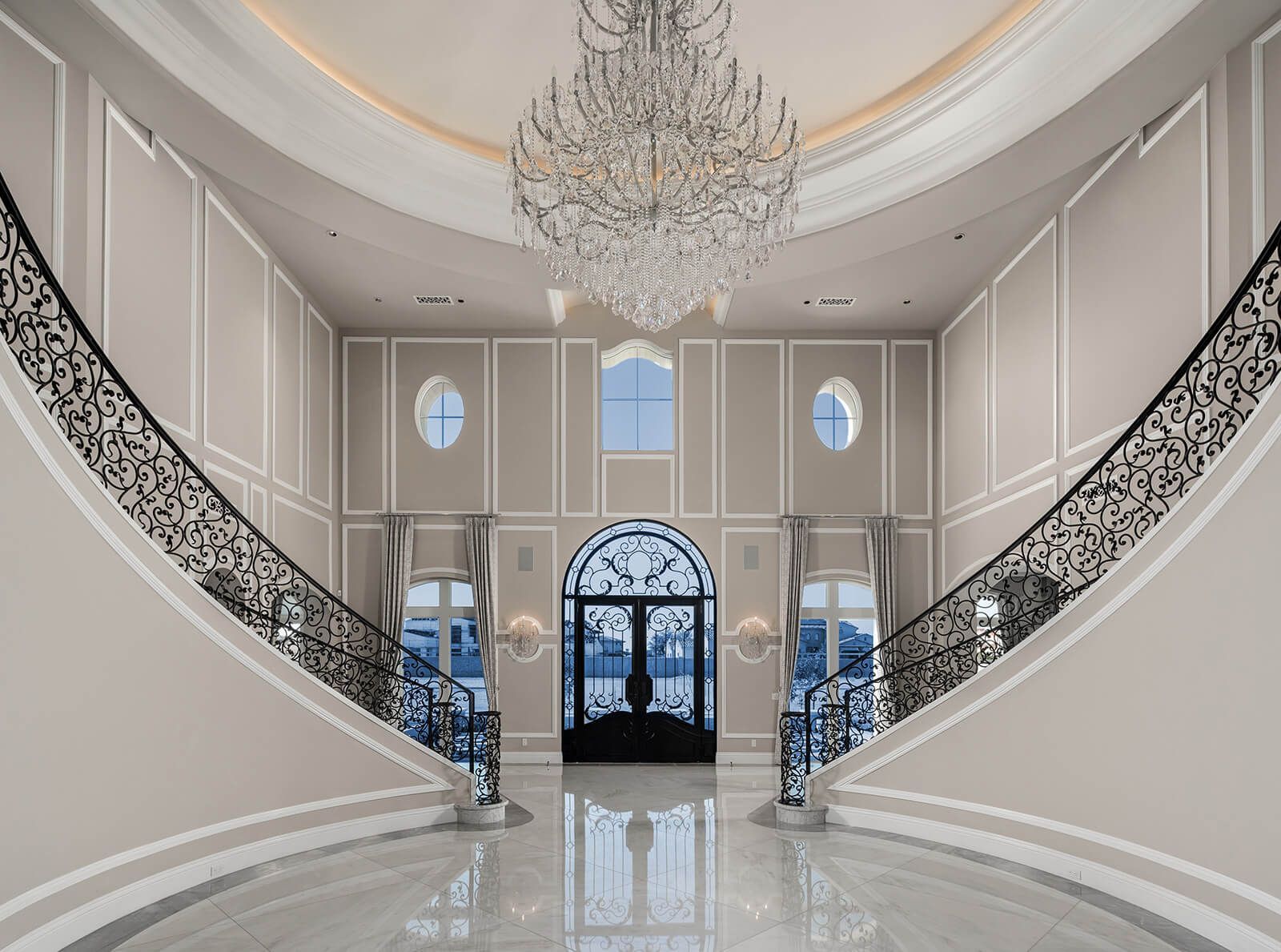 A large hallway with stairs and a chandelier hanging from the ceiling