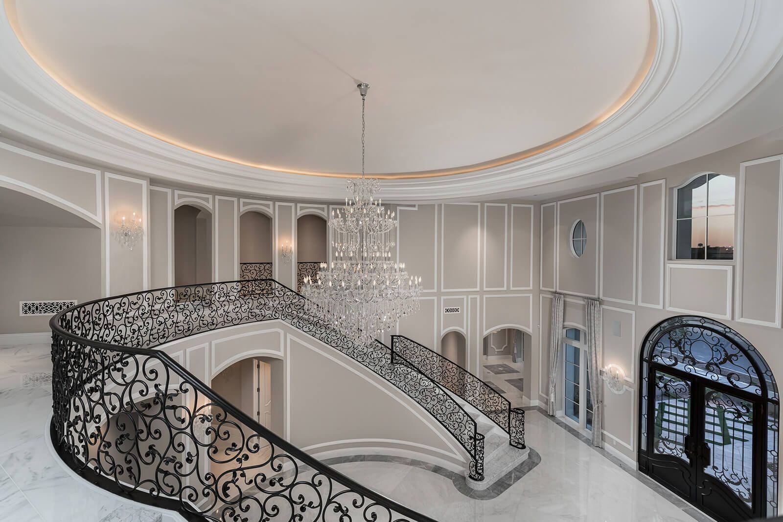 A large staircase with a wrought iron railing and a chandelier hanging from the ceiling.