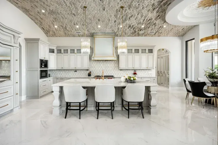 Luxury kitchen with arched ceiling, marble flooring, and elegant island seating