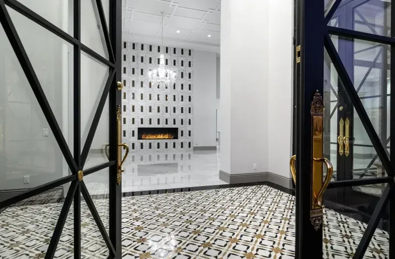 modern home entryway with glass doors, leading to formal living room with fireplace and chandelier