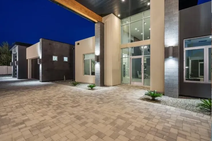 A large house with a lot of windows and a driveway at night.