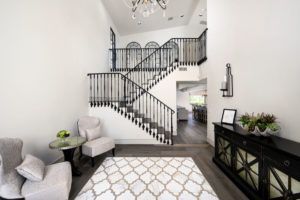 A living room with a rug , chairs , table and stairs.