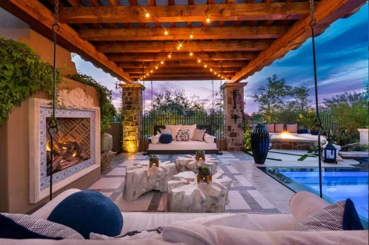 A patio with a fireplace and a swimming pool.