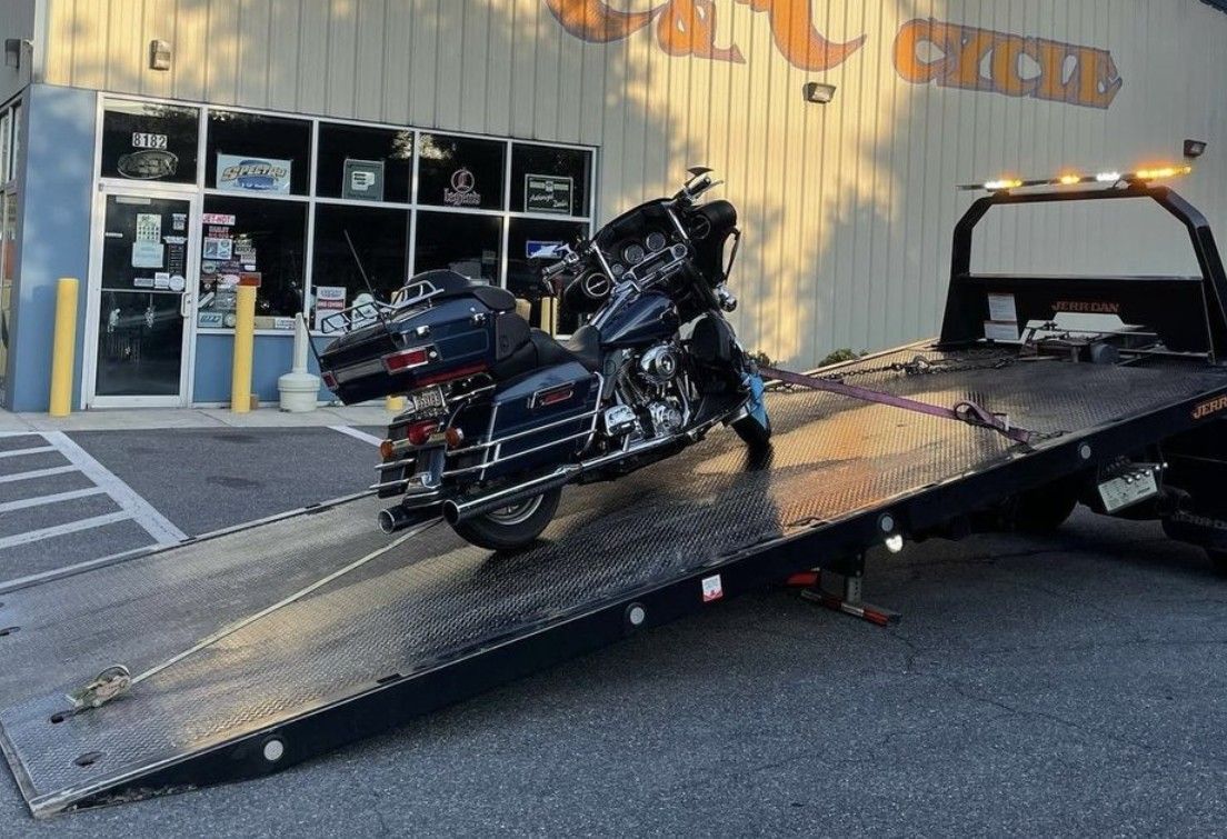 A black motorcycle on the back of a flatbed tow truck
