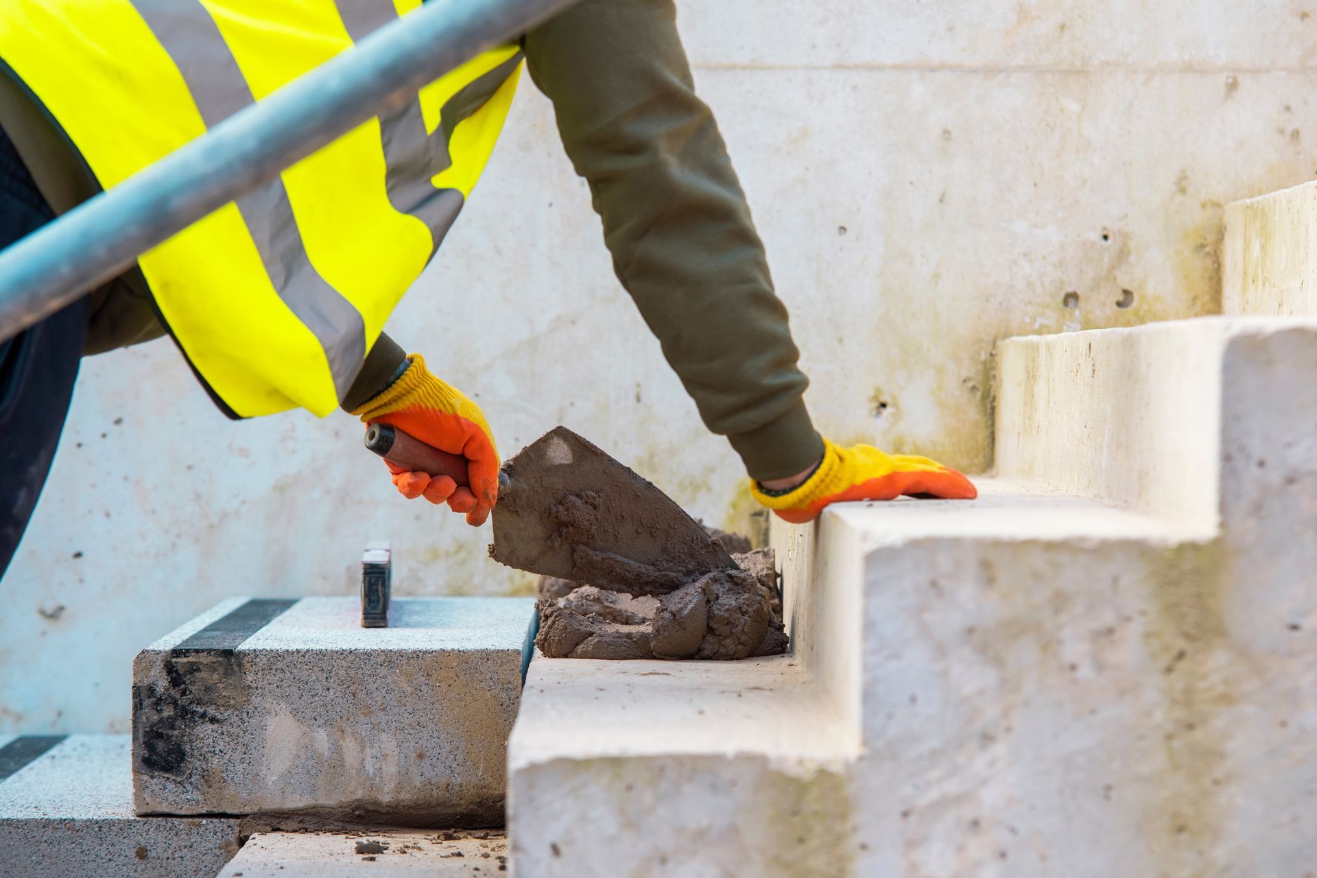 A construction worker is laying bricks on a set of stairs.