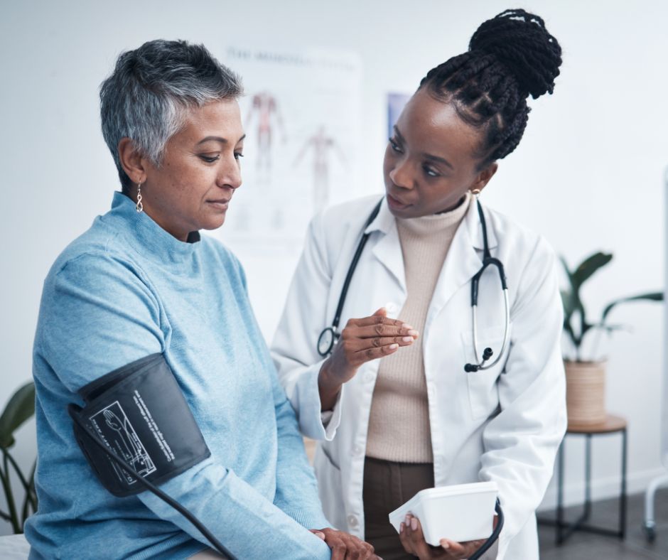 Doctor taking a patient's blood pressure; a medical setting. The doctor is explaining the reading.