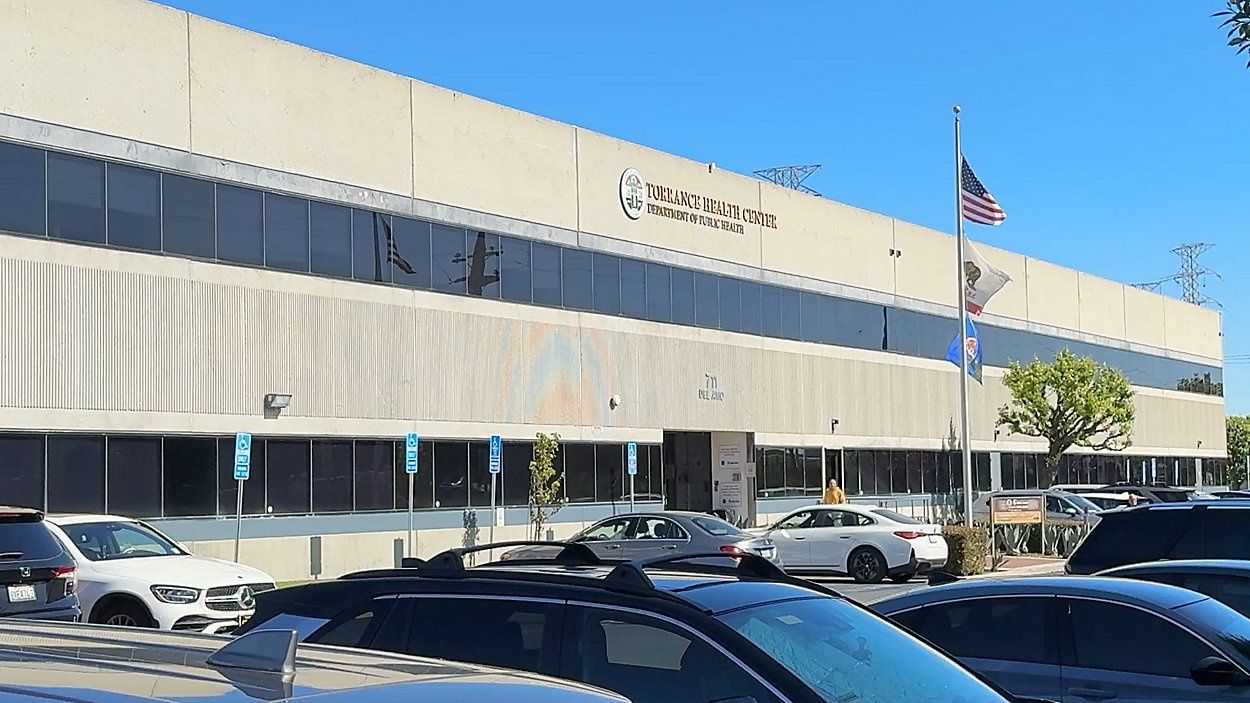 Office building with American flag, cars parked in front.