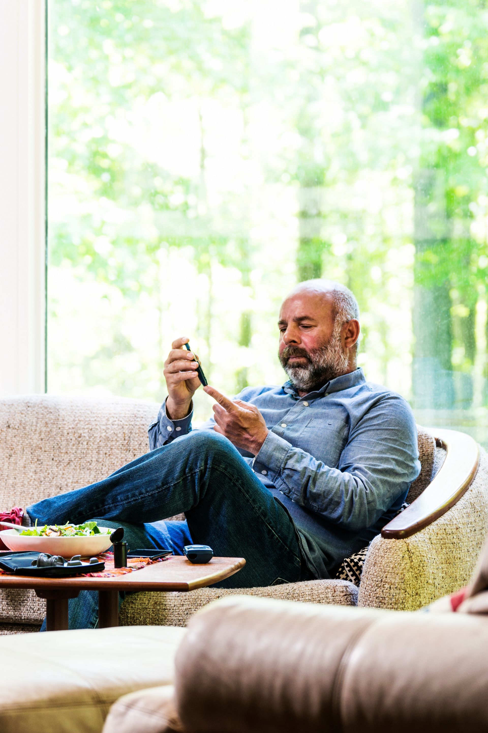 middle aged man at home checking his blood sugar