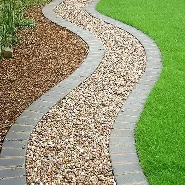 Winding gravel path with brick border, between brown mulch and green grass.