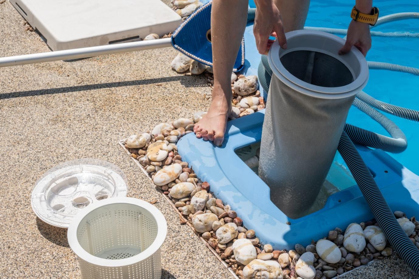 Person holding pool filter, cleaning it near the pool's edge.