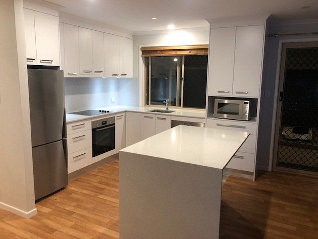 A Kitchen Featuring White Cabinets, Stainless Steel Appliances, and a Spacious Island — Expert Cabinetmaker on the Sunshine Coast QLD