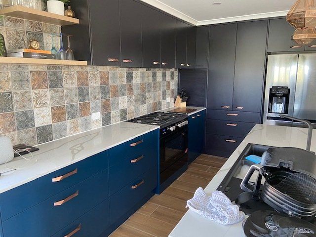 A Kitchen Featuring Blue Cabinets, White Countertops, a Stove, and a Refrigerator— Expert Cabinetmaker on the Sunshine Coast QLD