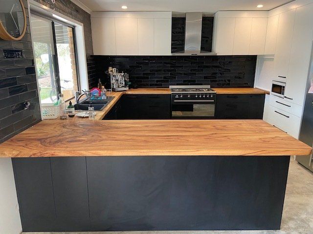A Kitchen With Black Cabinets and a Wooden Countertop, Blending Modern Elegance with Natural Warmth — Expert Cabinetmaker on the Sunshine Coast QLD