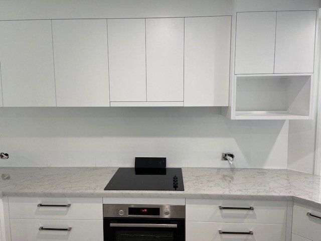 A Kitchen with White Cabinets and a Black Stove-top Oven — Expert Cabinetmaker on the Sunshine Coast QLD