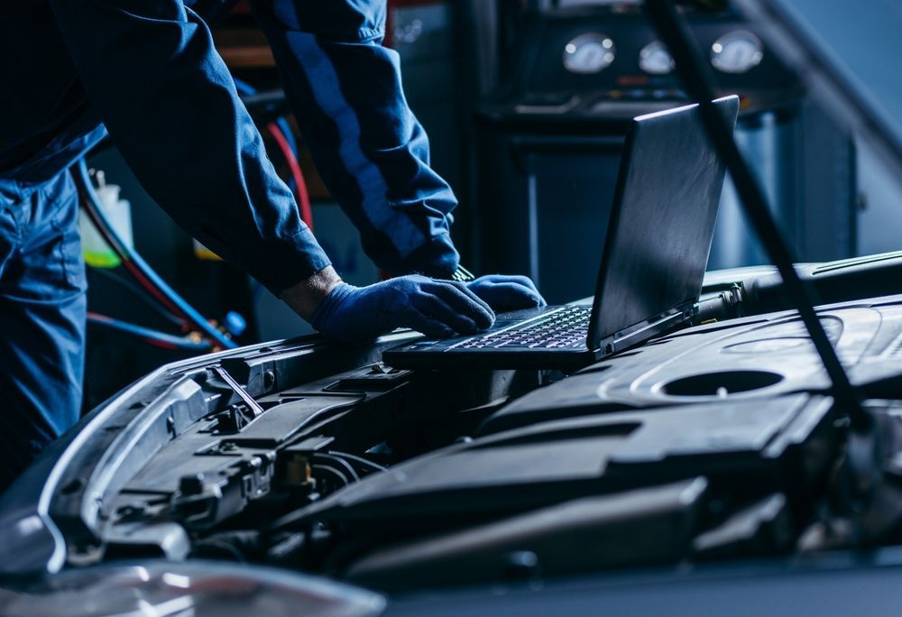 A Mechanic is Working on a Car With a Laptop — Dynamic Performance Systems in Bega, NSW