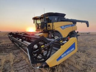 A New Holland Combine Harvester is in a Field at Sunset — Dynamic Performance Systems In Kelso, NSW