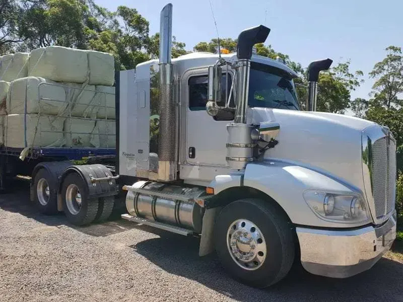 A White Semi Truck With a Trailer Full of Hay is Parked on the Side of the Road — Dynamic Performance Systems In Kelso, NSW