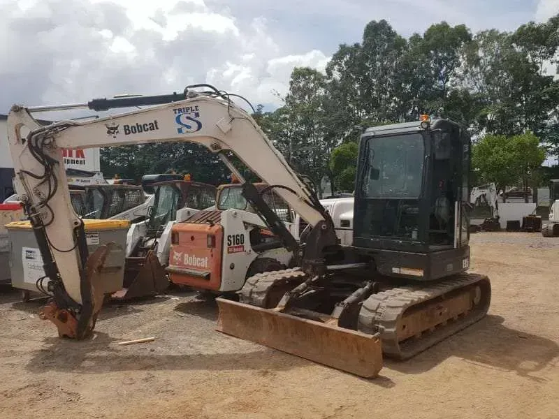 A Bobcat Excavator is Parked in a Dirt Lot — Dynamic Performance Systems In Kelso, NSW