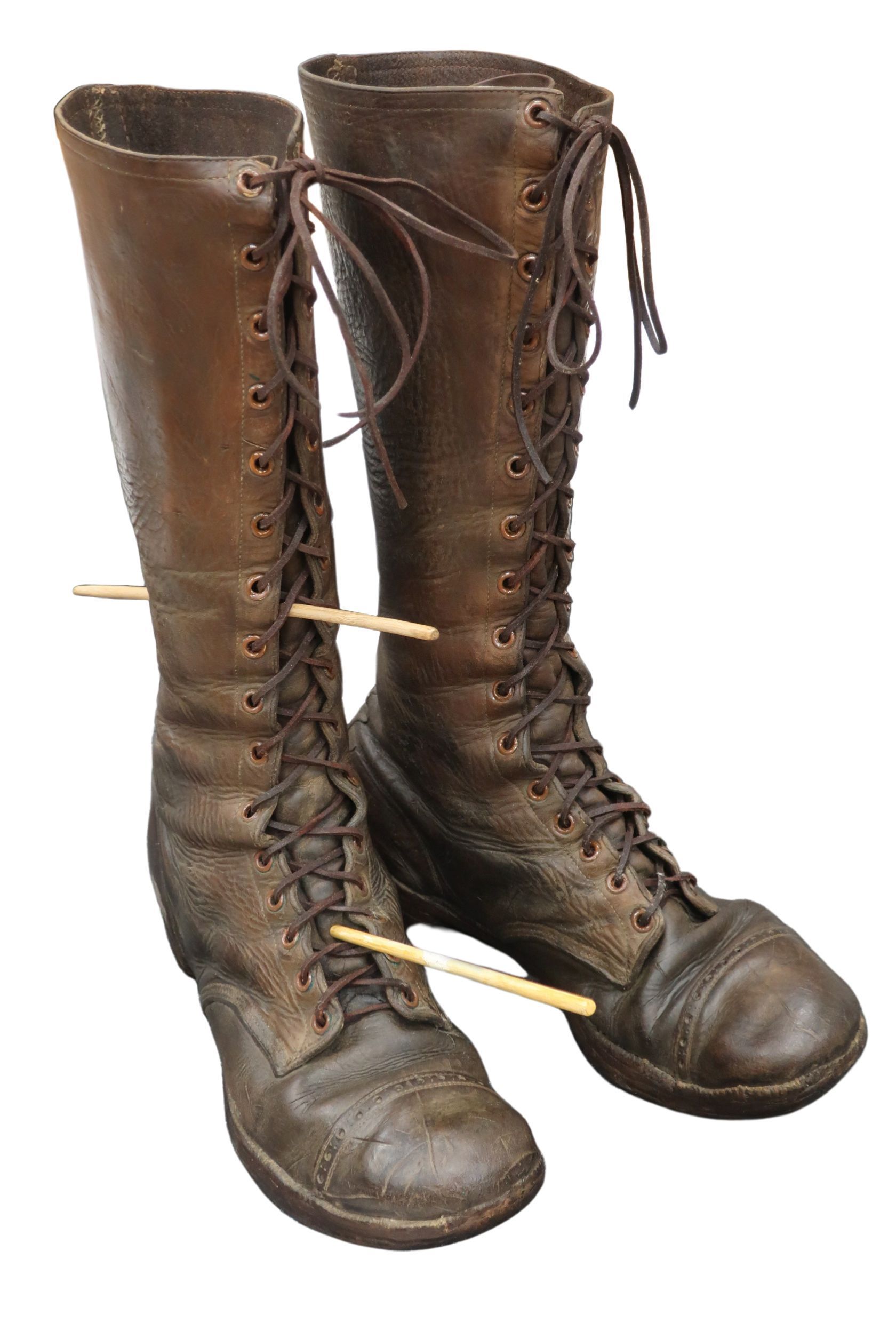 A pair of brown lace up boots with a pencil sticking out of them