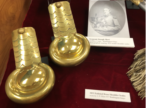 Two gold brass Civil War-era shoulder scales on red cloth, with photo of August Rudolph.