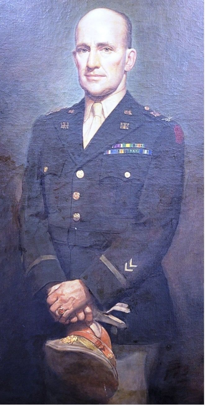 Portrait of a bald military officer in uniform, holding a hat, with a serious expression.
