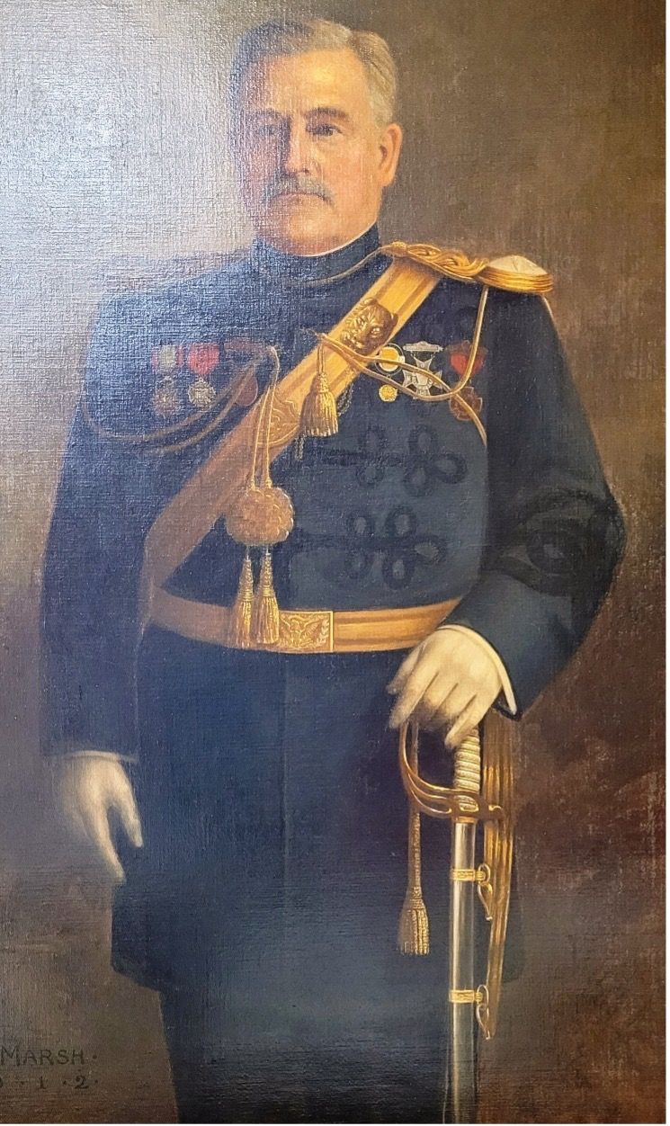 Portrait of a man in a dark military uniform with medals, a sash, and a sword. He has a mustache and is holding a sword.