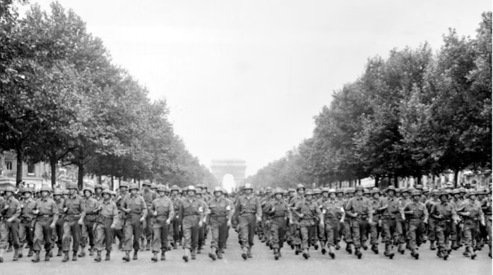 A large group of people marching down a street with trees in the background
