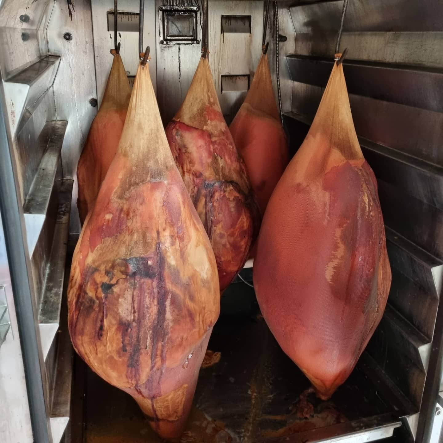Five Cured Hams Hanging Inside a Stainless Steel Curing Cabinet — West High Street Boutique Butchery In Coffs Harbour, NSW