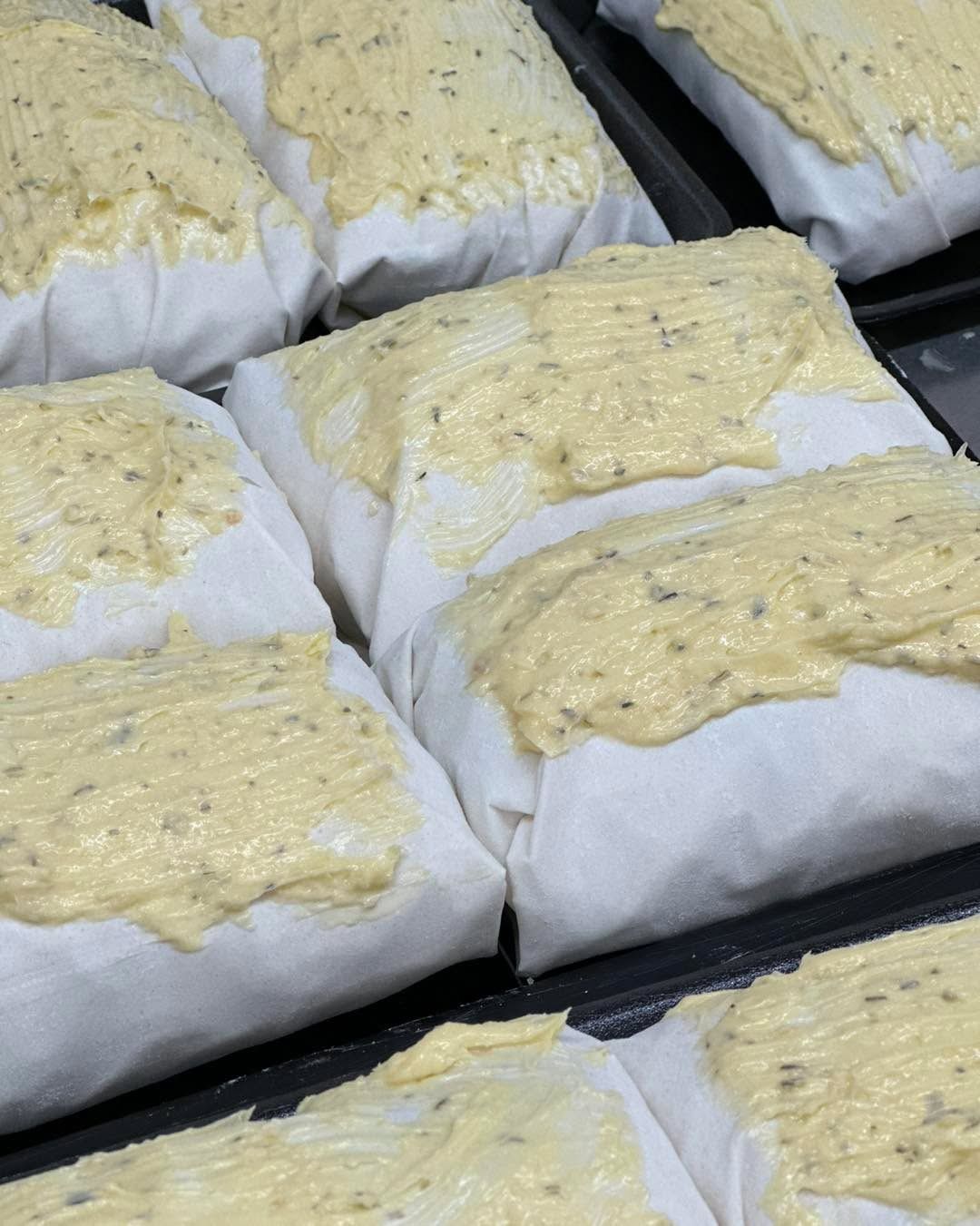 Butter-topped food wrapped in white paper, arranged on a black tray.