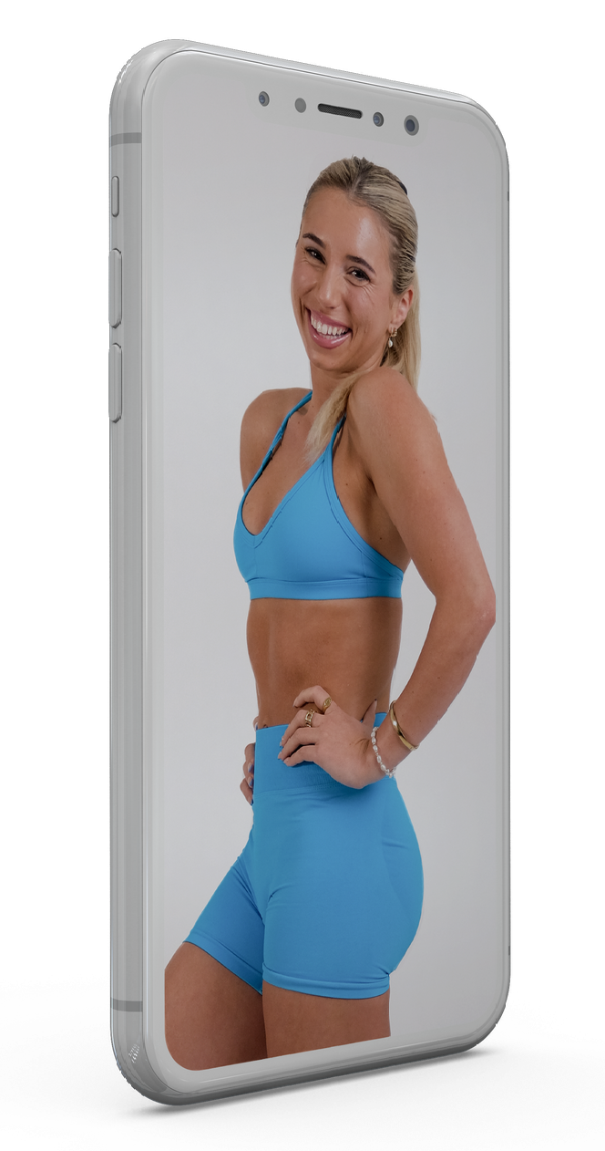 A woman in a blue sports bra and shorts is standing on a cell phone.