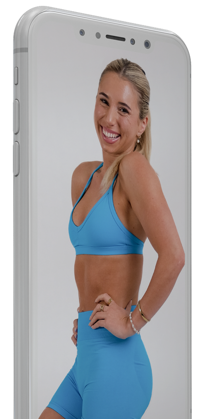 A woman in a blue sports bra and shorts is standing on a cell phone.