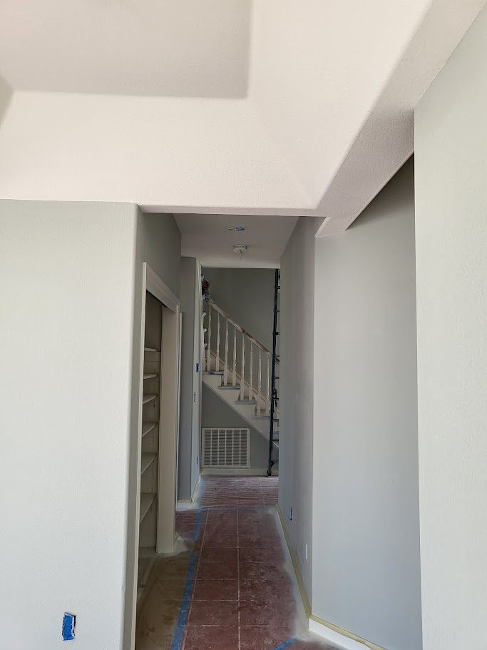 Hallway with light blue walls, leading to stairs. Unfinished construction with exposed flooring.