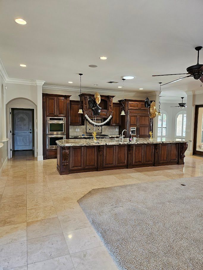 Spacious kitchen with dark wood cabinets, large island, and light-colored floors and walls.