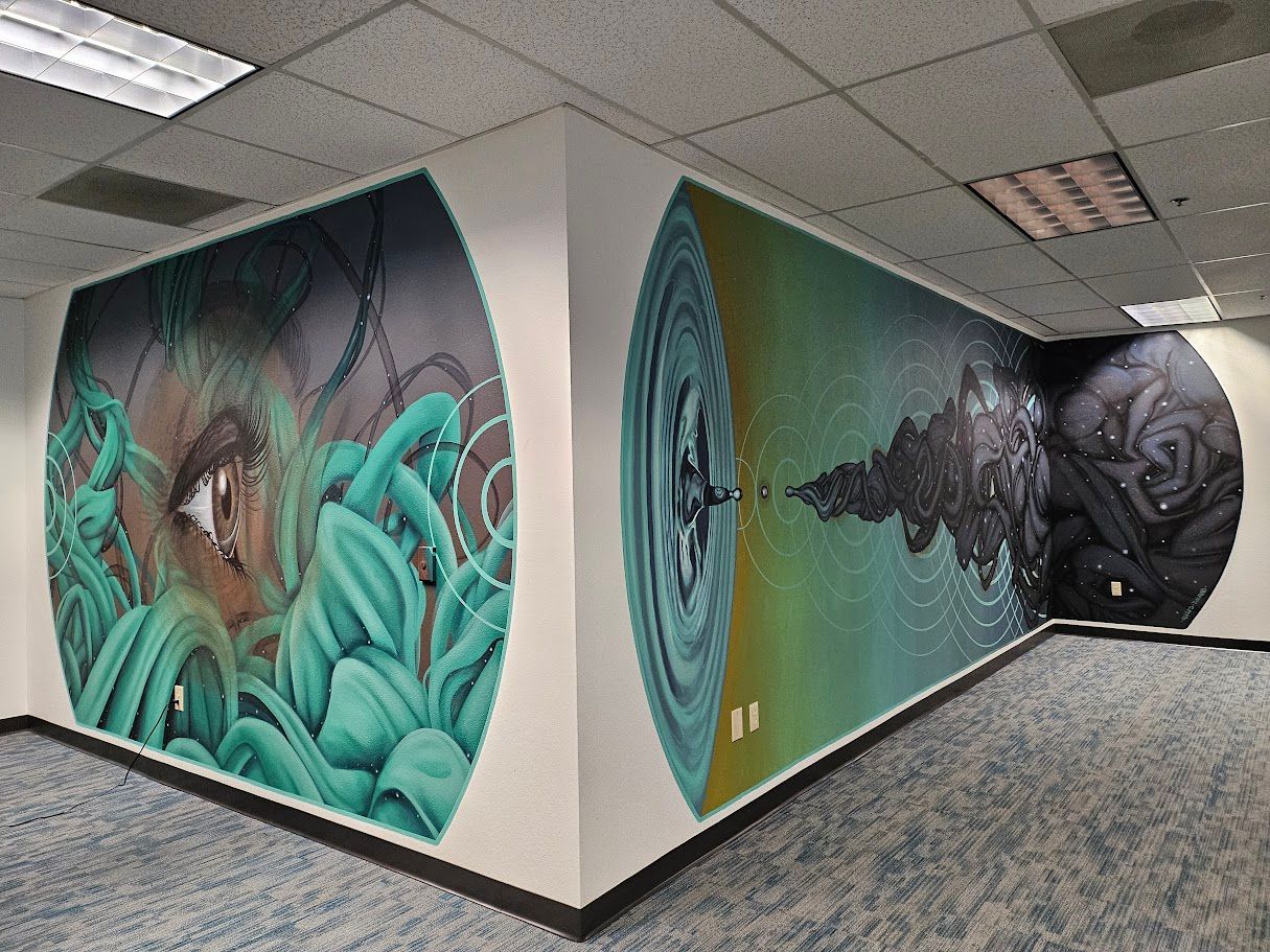 Mural on office walls with abstract imagery: eye, water ripples, and dark shapes in shades of green, blue, and black.